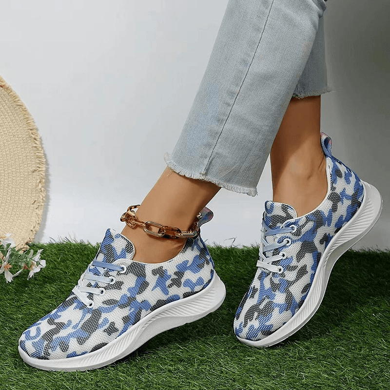 Women's breathable mesh non-slip sports shoes with lace-up, featuring a blue camouflage pattern, worn with light jeans on green grass.